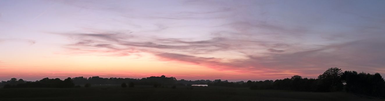 Beautiful high resolution panorama of orange and red sunset clouds in the evening sky.