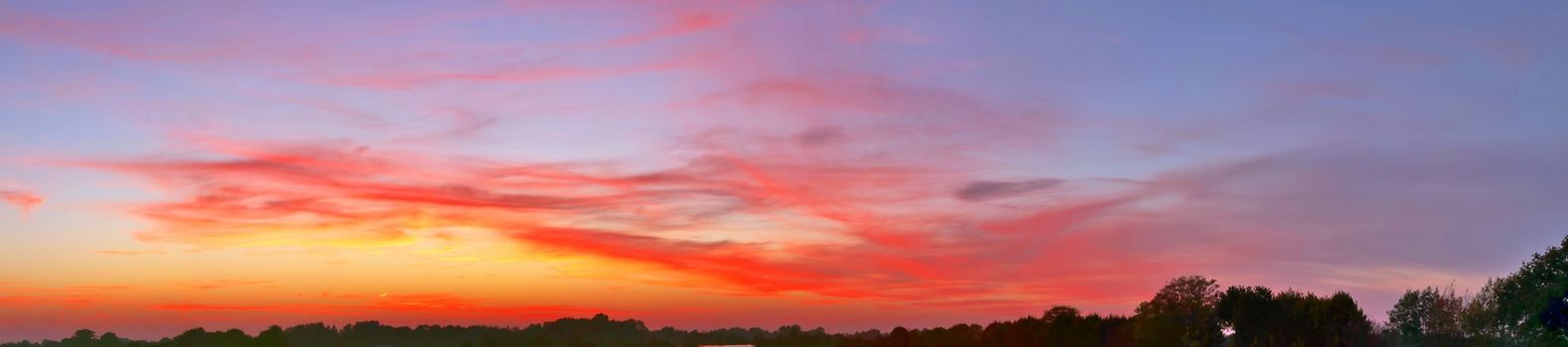 Beautiful high resolution panorama of orange and red sunset clouds in the evening sky.