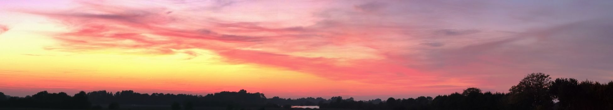 Beautiful high resolution panorama of orange and red sunset clouds in the evening sky.