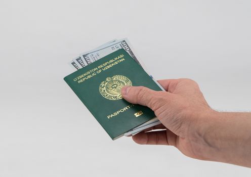 Hand holds out Uzbekistan passport with usa dollars. Concept - briber and corruption