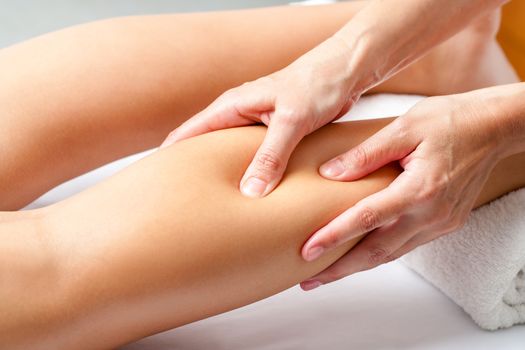 Macro close up of Hands applying pressure with fingers on calf muscle. Osteopath doing healing massage on female leg.