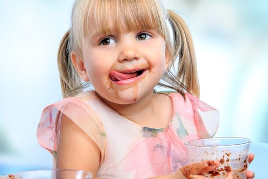 Close up portrait of Little girl with messy face drinking chocolate milkshake at home.