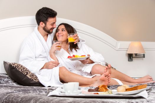 Close up portrait of Young couple on honeymoon in hotel room. Couple enjoying room service with breakfast tray.