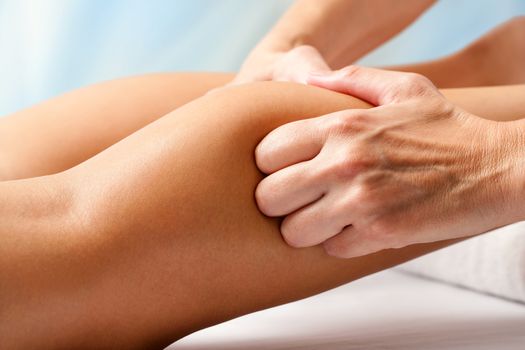 Macro close up of Physiotherapist hands massaging female calf muscle.