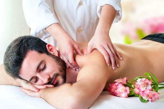 Close up of therapist hands doing upper back and shoulder massage on young man.