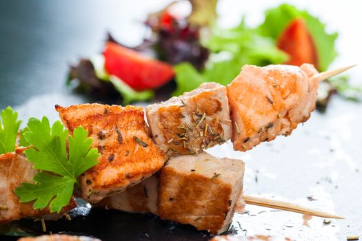 Macro close up of appetizing char broiled salmon and tuna skewer seasoned with herbs.