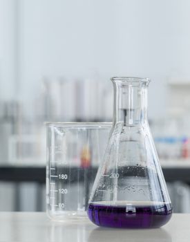 Erlenmeyer Flask contains purple liquid chemicals on a white laboratory table. Potassium Permanganate Liquid.