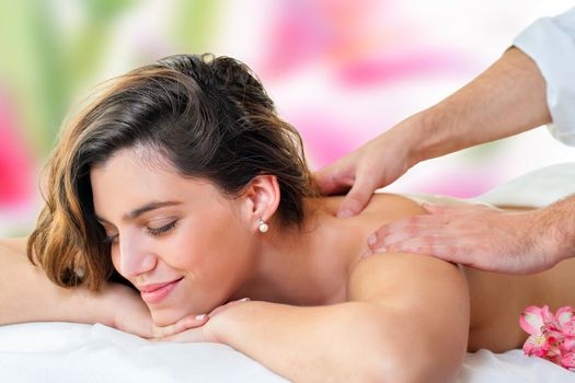 Close up of young attractive woman enjoying back massage. Therapist hands massaging shoulders and neck.