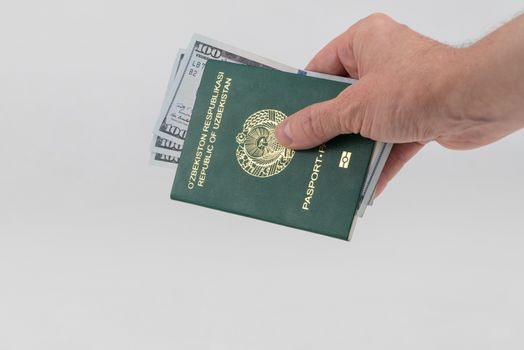 Hand holds out Uzbekistan passport with usa dollars. Concept - briber and corruption