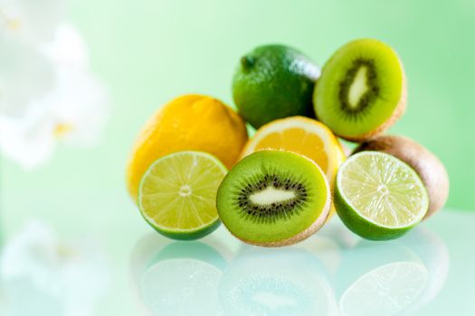 Macro close up of Multiple Citrus fruits on table against green background.