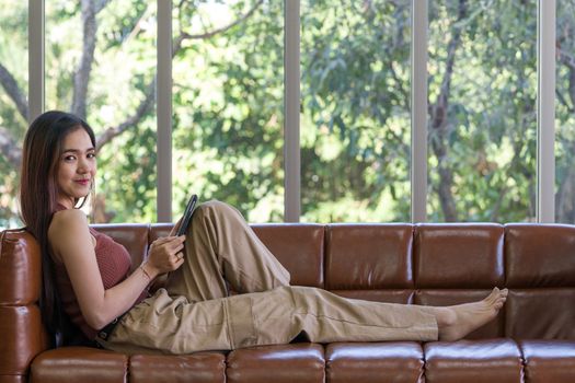 Asian woman spend holidays in the living room. The young woman is checking email using a tablet computer.