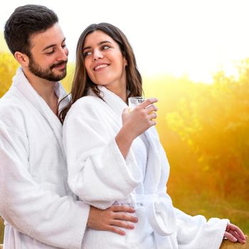 Close up of Cute young Couple in bathrobe ready for spa treatment. Couple standing on balcony against bright yellow rural background.
