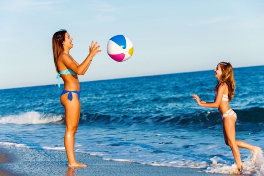 Close up full length portrait of two Young girls playing with inflatable ball on beach.