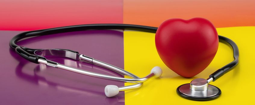 Toy heart and stethoscope on a colored background. Concept healthcare. Cardiology - care of the heart