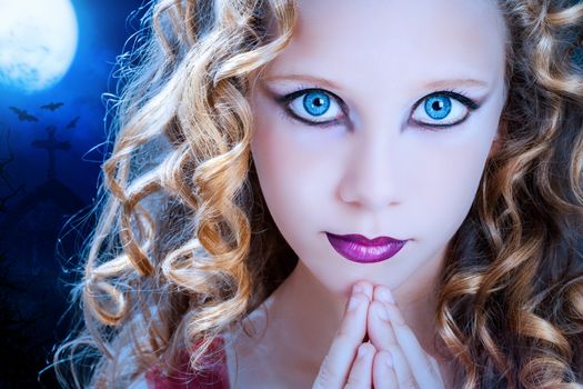 Extreme close up facial portrait of young Girl with big blue eyes. Beauty cosmetic make up on pre teen with graveyard at full moon in background.