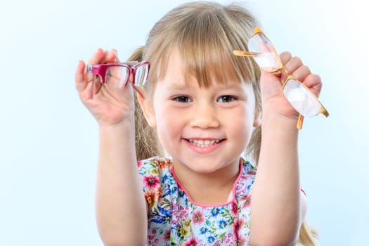 Close up portrait of infant holding two glasses at eye test.