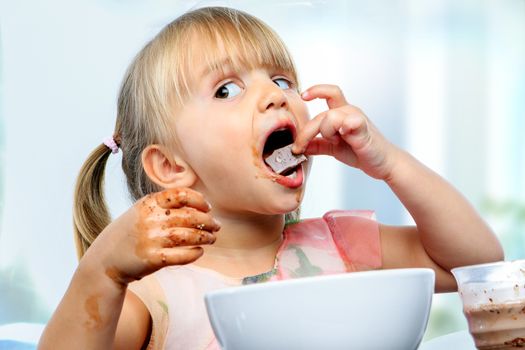 Close up portrait of infant eating and messing with chocolate at breakfast.