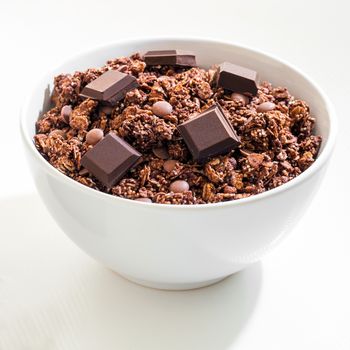 Macro close up of chocolate muesli bowl wit pieces of dark chocolate.