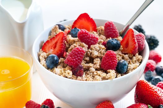 Macro close up of Healthy cereal breakfast with red fruits.Bowl of crunchy
muesli and fresh orange juice.