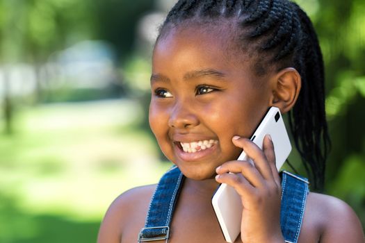 Close up outdoor portrait of cute little african girl having conversation on smart phone.