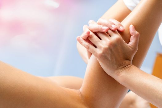 Macro close up of osteopath massaging female calf muscle. Hands manipulating lower leg muscle.