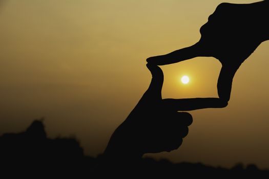 Hands making frame with sunset. Close up of woman hands making frame gesture.