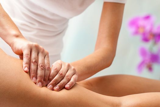 Therapist doing rehabilitation massage with hands on female hamstrings.