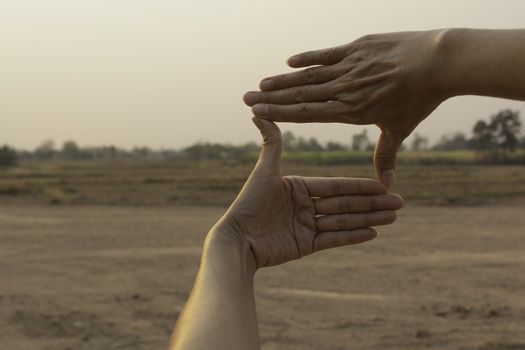 Hands making frame with sunset. Close up of woman hands making frame gesture.
