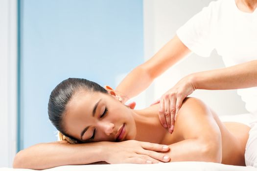 Close up of young woman enjoying relaxing body massage. Therapist doing manipulative treatment on shoulders.