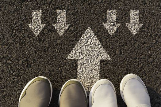 Top view of man wearing white shoes choosing a way marked with white arrows. Chooses the right path concept.
