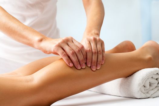 Detail of hands massaging human calf muscle.Therapist applying pressure on female leg.