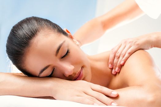 Close up of Young woman enjoying spa treatment. Therapist doing manipulative massage on shoulders.