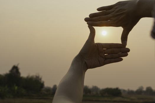 Hands making frame with sunset. Close up of woman hands making frame gesture.