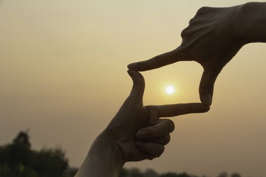 Hands making frame with sunset. Close up of woman hands making frame gesture.