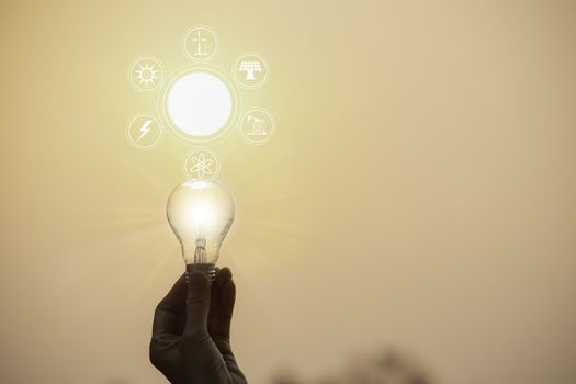 Hand hold a light bulb on sunset background for saving energy and creative concept.