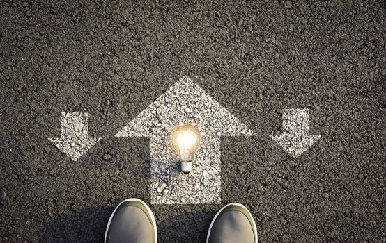 Top view of man wearing white shoes choosing a way marked with white arrows and light bulb. Chooses the right path concept.