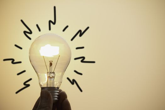 Hand hold a light bulb on sunset background for saving energy and creative concept.