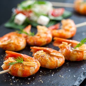 Macro close up of giant aromatic prawn tails spiced with natural herbs and grilled on wood skewer.