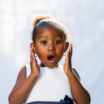 Portrait of cute African girl with shocking face expression.Isolated against light background.