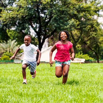 Action portrait of African kids playing and running together in park.