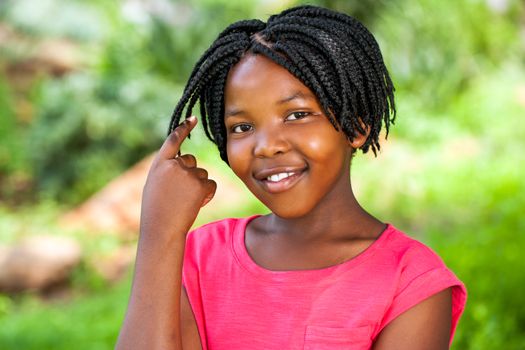 Close up portrait of Cute African girl showing braided hair outdoors in park.