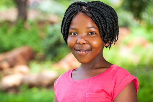 Close up portrait of young African girl with braided hairstyle outdoors in park.