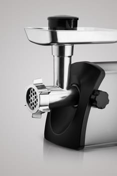 household electric meat grinder with nozzle on light grey background, close-up. kitchen appliances