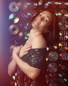 young Caucasian woman posing on a shiny flickering dark background, girl looking at the camera