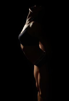 silhouette of a beautiful young girl of athletic appearance, body curved back, arms laid back, low key