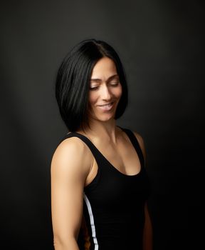 portrait of a beautiful young woman with black hair on a dark background, girl smiling
