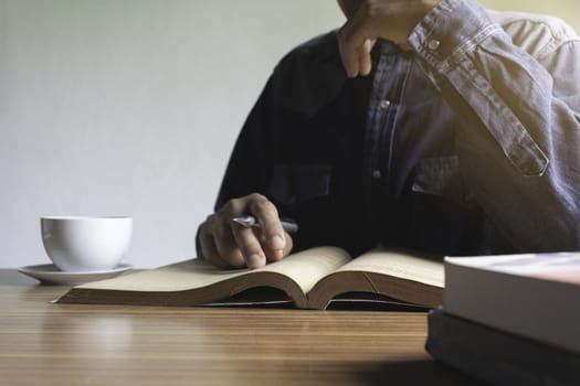 A Man reading a book enjoys of rest. Man sitting and reading a book. Concepts of rest, education and comfort.
