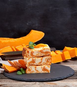 stack of square pieces of baked cheesecake cottage cheese with pumpkin and fresh pieces of vegetable