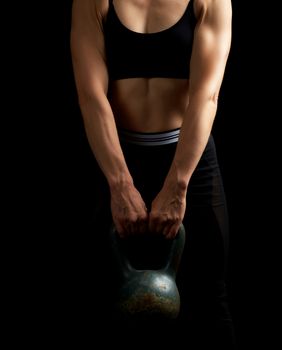 girl of athletic appearance holds an iron kettlebell in front of her, strength sports, low key