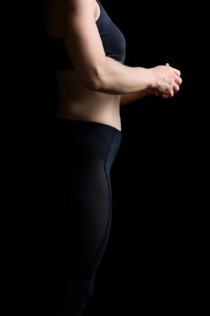 body of a girl of athletic appearance in a black bra and leggings, athlete stands sideways, low key